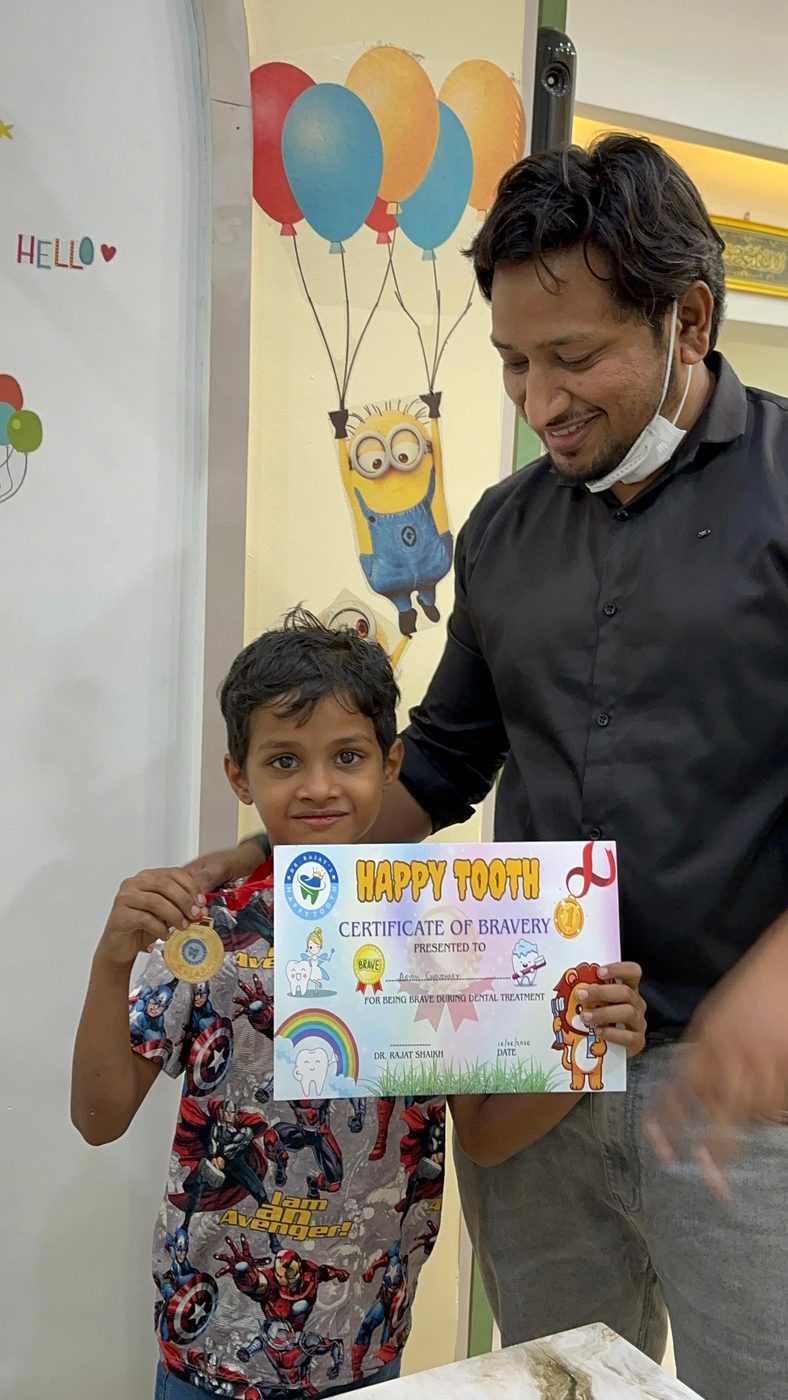 A happy child patient proudly holding a Happy Tooth Certificate of Bravery, Pune